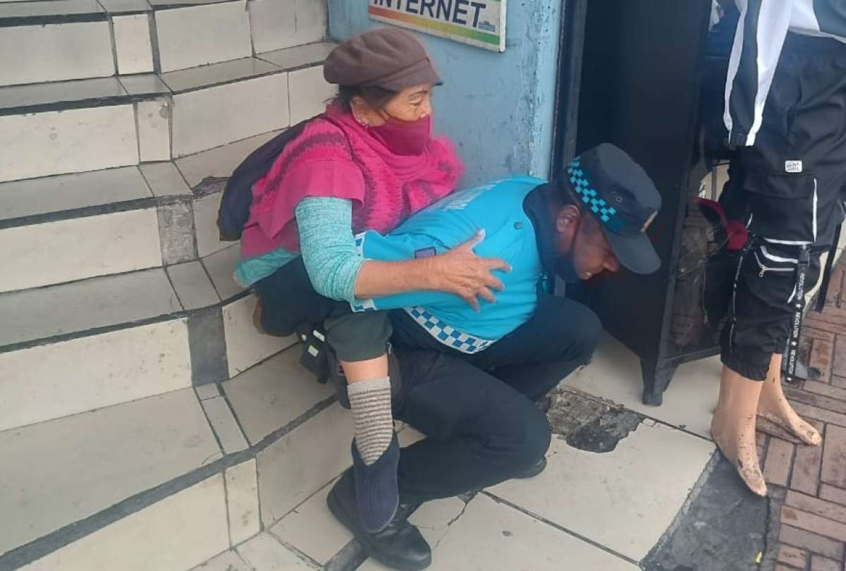 Agente de control de Quito carg&oacute; a una mujer en su espalda