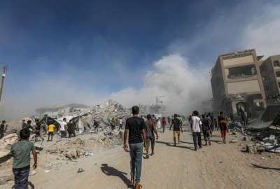 Los palestinos pasan junto a los escombros mientras el humo se eleva del edificio residencial al-Roya tras un ataque a&eacute;reo israel&iacute; en el oeste de la ciudad de Gaza, Franja de Gaza, 8 de septiembre de 2025.