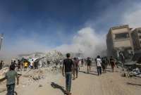 Los palestinos pasan junto a los escombros mientras el humo se eleva del edificio residencial al-Roya tras un ataque a&eacute;reo israel&iacute; en el oeste de la ciudad de Gaza, Franja de Gaza, 8 de septiembre de 2025.